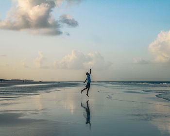Full length of man walking at beach against sky during sunset
