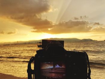 Man photographing at beach during sunset