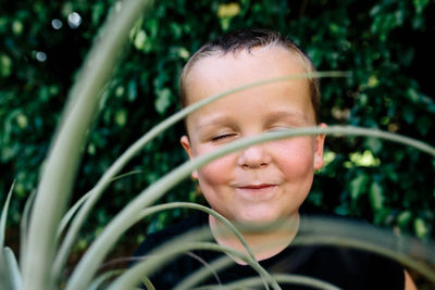 Close-up of cute boy with eyes closed sitting in yard