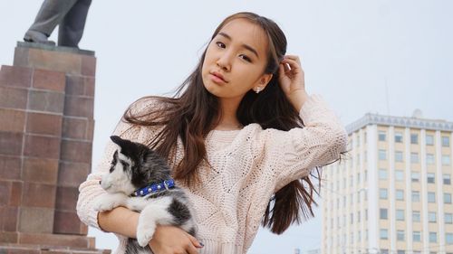 Low angle view of young woman in front of buildings