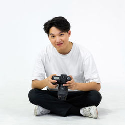 Portrait of young man photographing against white background