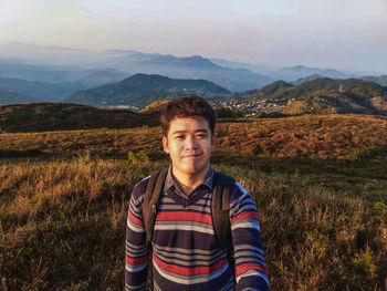 Portrait of young man standing on mountain during sunset