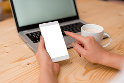 Midsection of person holding smart phone on table