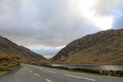 Road by mountains against sky