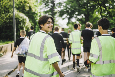 Portrait of smiling boy walking with friend wearing reflective clothing