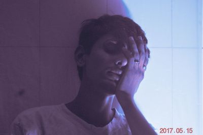 Portrait of young man looking away against wall