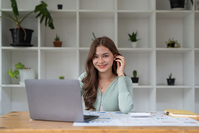 Portrait of young woman using laptop at table