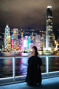 Rear view of woman standing in city at night