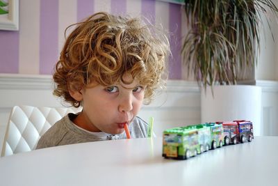 Portrait of boy drinking while sitting on table at home