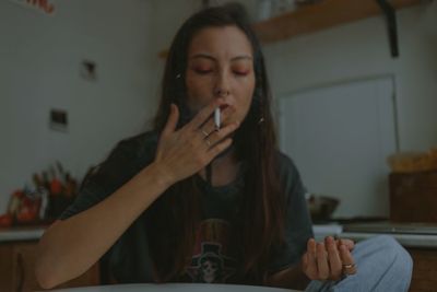Sad woman with the cigarette and smartphone at home