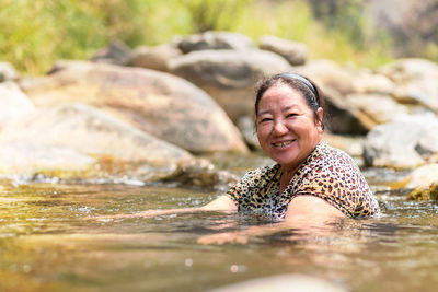 Portrait of smiling woman swimming in lake
