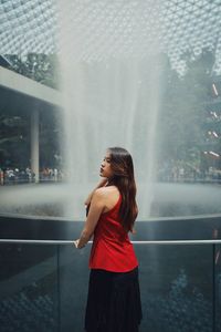 Rear view of woman standing by fountain outdoors