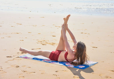 Woman lying down on sand at beach