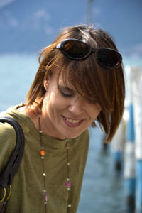 Close-up of smiling young woman standing against lake