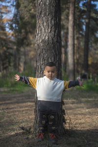 Full length of kid with arms raised in forest