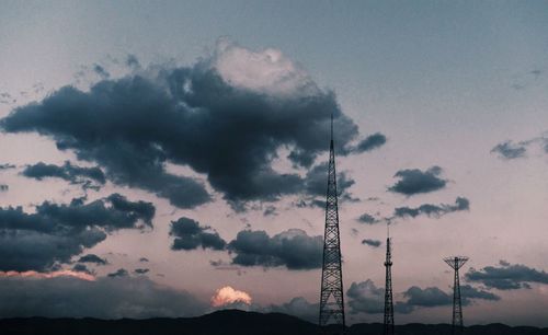 Low angle view of silhouette electricity pylon against sky