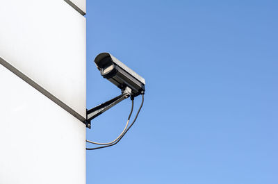 Low angle view of telephone pole against clear blue sky