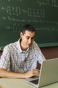 Math teacher using laptop in classroom