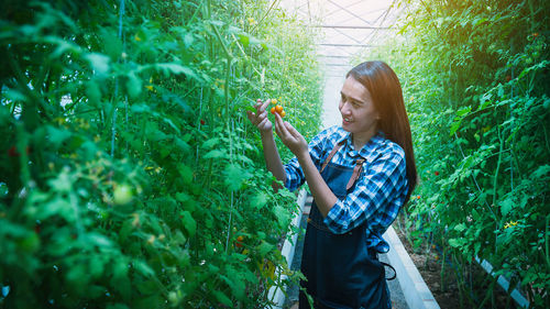 Young woman smiling while standing against plants