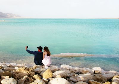 Couple clicking themselves with camera phone against the sea