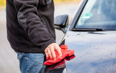 Midsection of man holding while standing by car