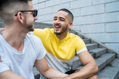 Happy gay couple sitting on steps in city