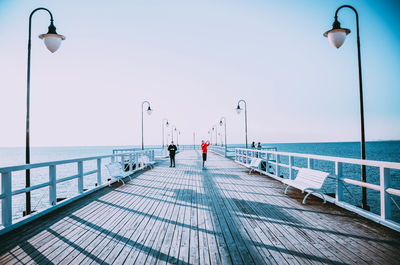 People on street by sea against clear sky