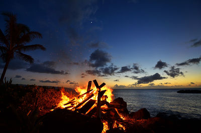 Bonfire on beach against sky at sunset