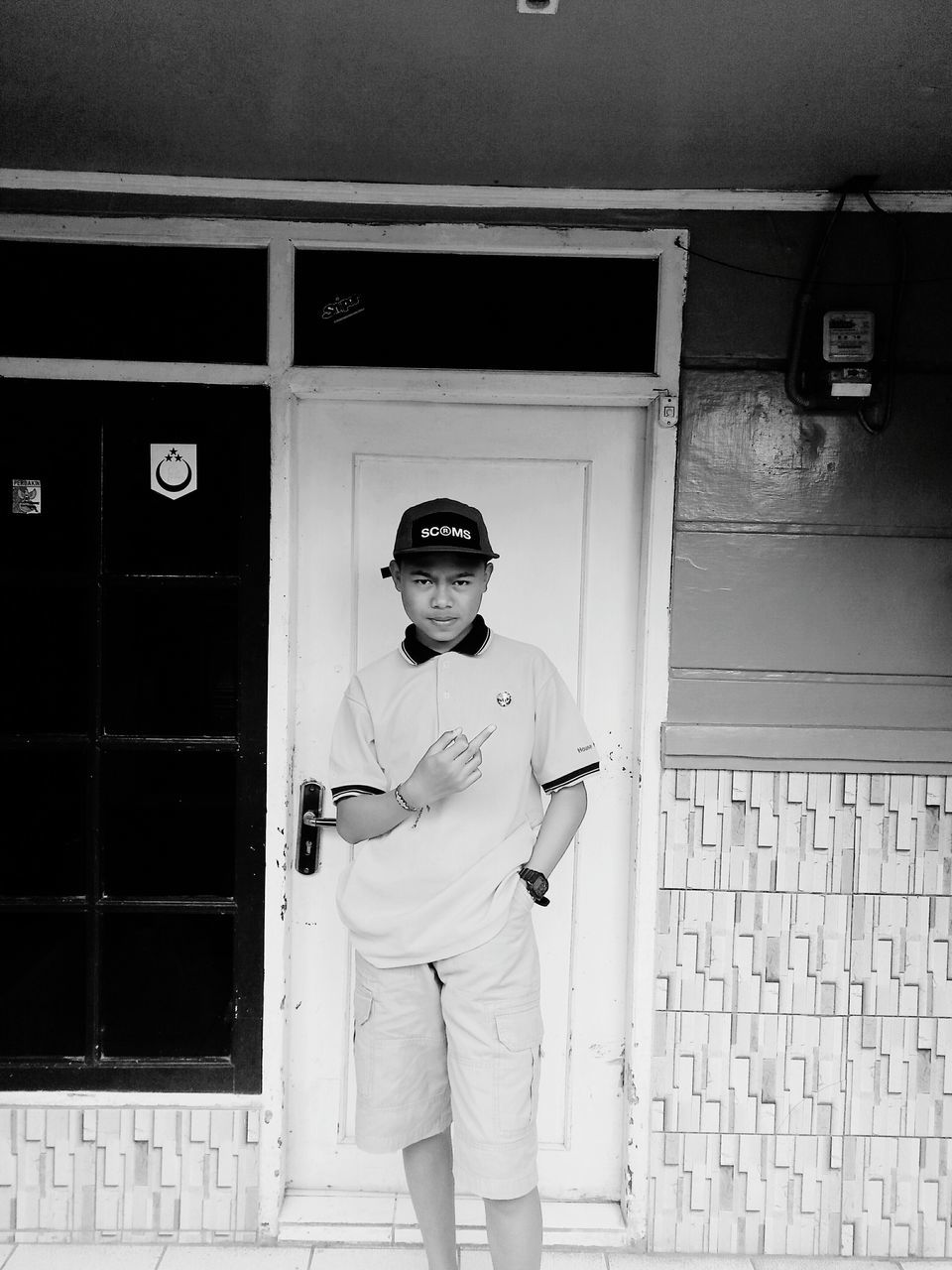 PORTRAIT OF YOUNG MAN STANDING BY WALL