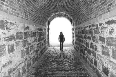 Rear view of woman walking in tunnel