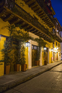 Illuminated road amidst buildings in city at night