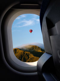 View of hot air balloon against sky seen through airplane window