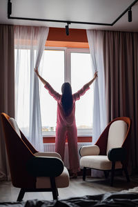 Rear view of woman standing by window