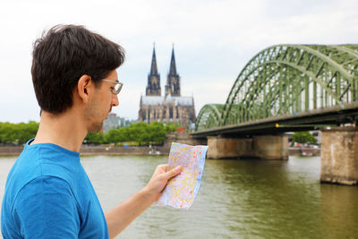 Man holding map against bridge over river in city