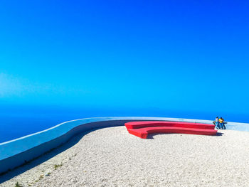 Red umbrella on beach against clear blue sky