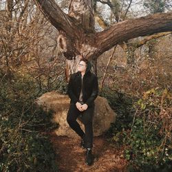 Full length of man on tree trunk in forest