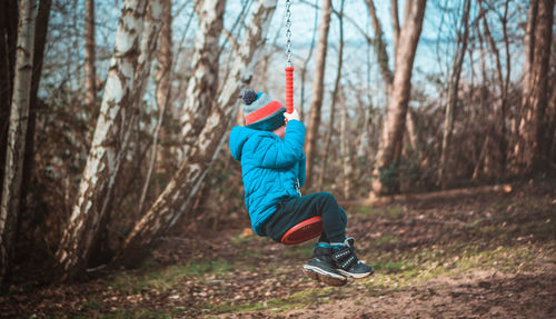 Rear view of boy playing on the playground during winter