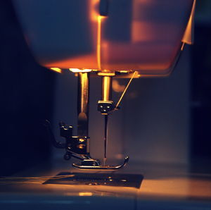 Close-up of illuminated sewing machine in darkroom