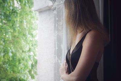 Side view of woman standing by window