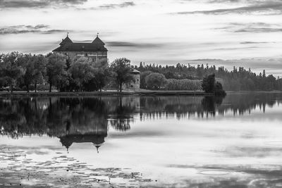 Reflection of house in lake against cloudy sky