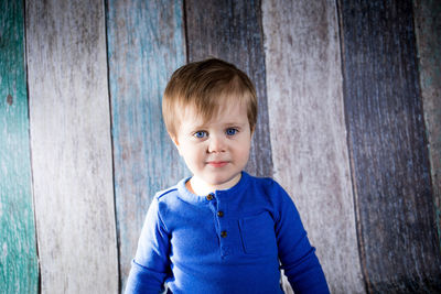 Portrait of cute boy standing against blue wall