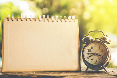 Close-up of blank calendar by alarm clock on table