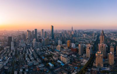 Aerial view of buildings in city against sky during sunset