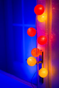 Low angle view of illuminated lights hanging against wall at home