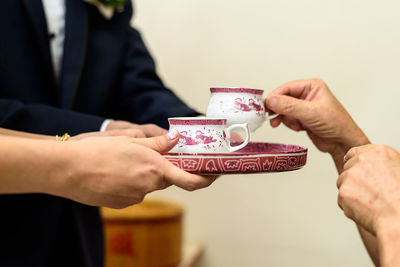 Cropped hands of woman serving drink to guest during tea ceremony