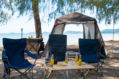 Empty chairs and tables and table in front of beach