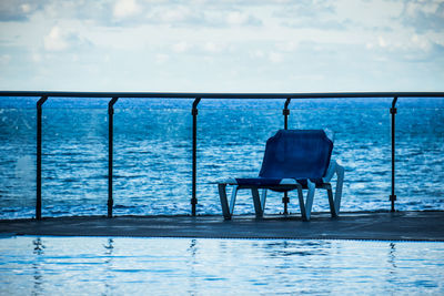 Empty deck chair on pier over sea