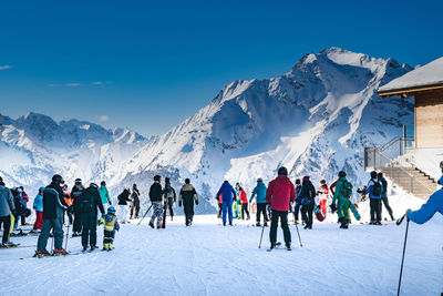 People on snow covered field against sky