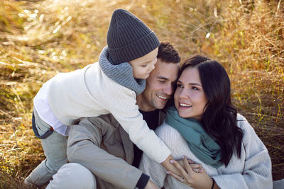 Stylish family with a boy child on a field in the dry grass in autumn