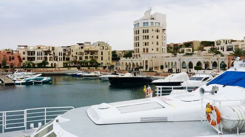 Boats moored in canal amidst buildings in city against sky